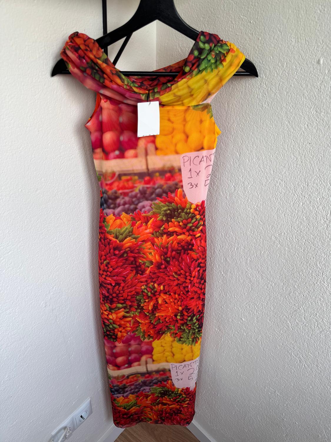 Long dress with colourful fruit and vegetable print, hanging on a black hanger. Visible text: "SPICY 1x2 3x5".
