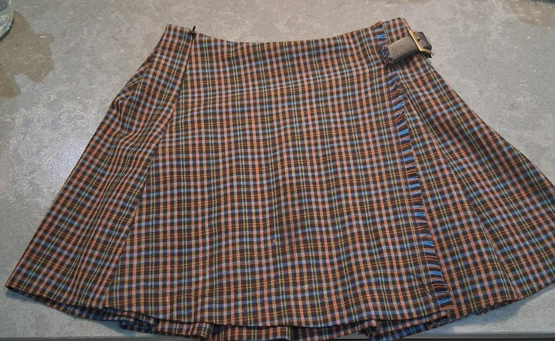 Brown and blue checked skirt with a metallic buckle at the waist, on a grey surface.