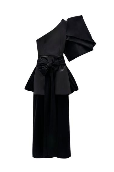Front view of an asymmetrical black dress with a tie at the waist and a voluminous sleeve.