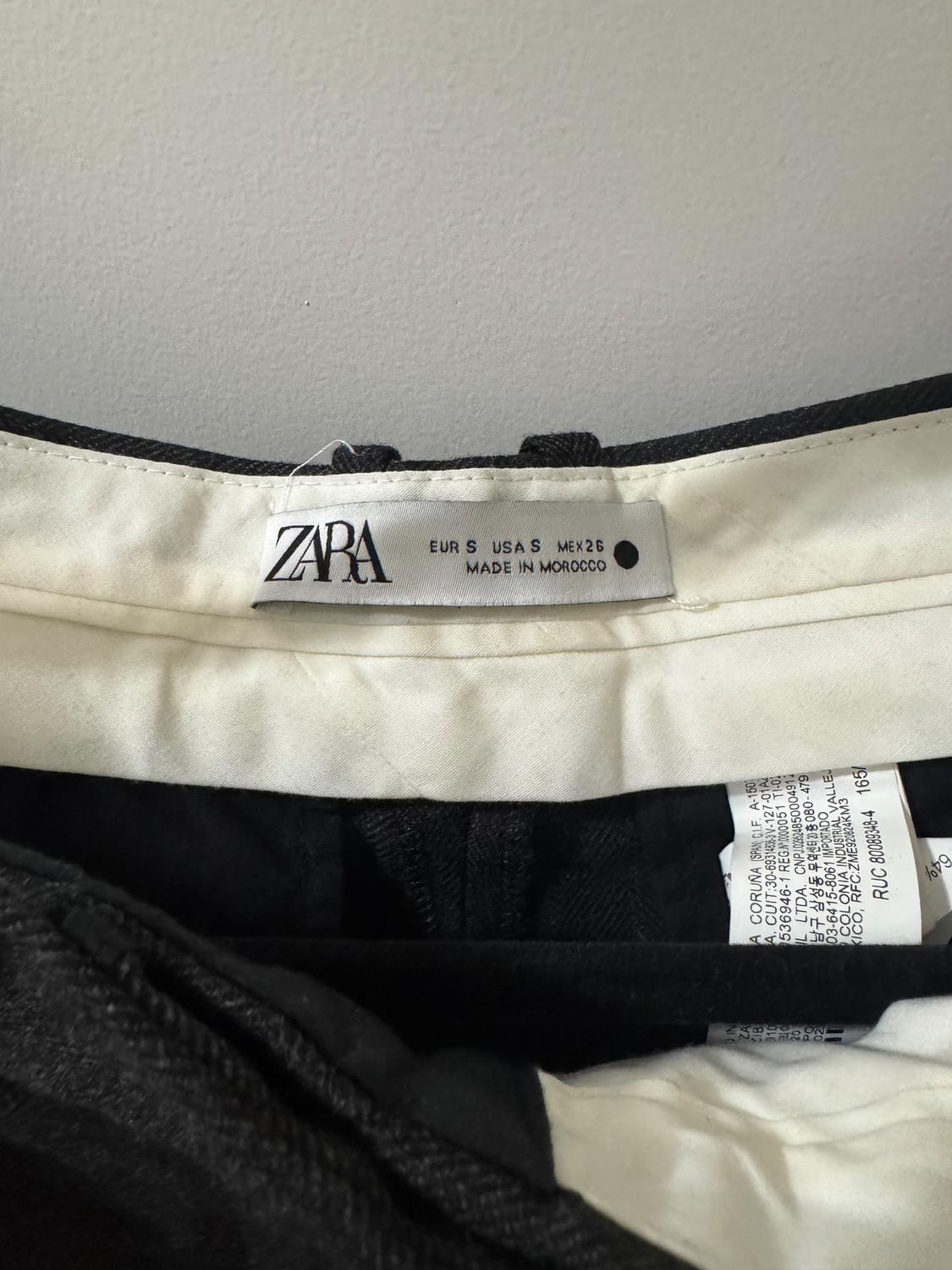 Zara clothing tag, size EUR S, USA S, MEX 26, made in Morocco, on a black and white background.