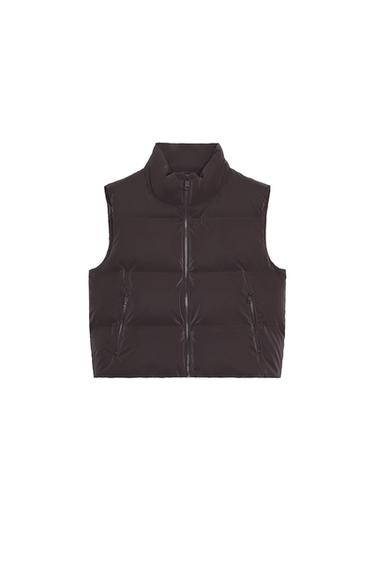 Front view of a sleeveless brown quilted gilet, with a high neck, side zip pockets, and a front zip fastening.