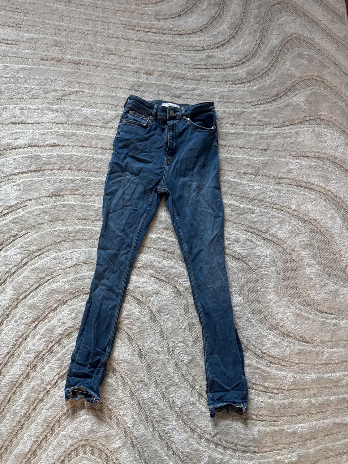 Front view of blue jeans with pockets and button closure.