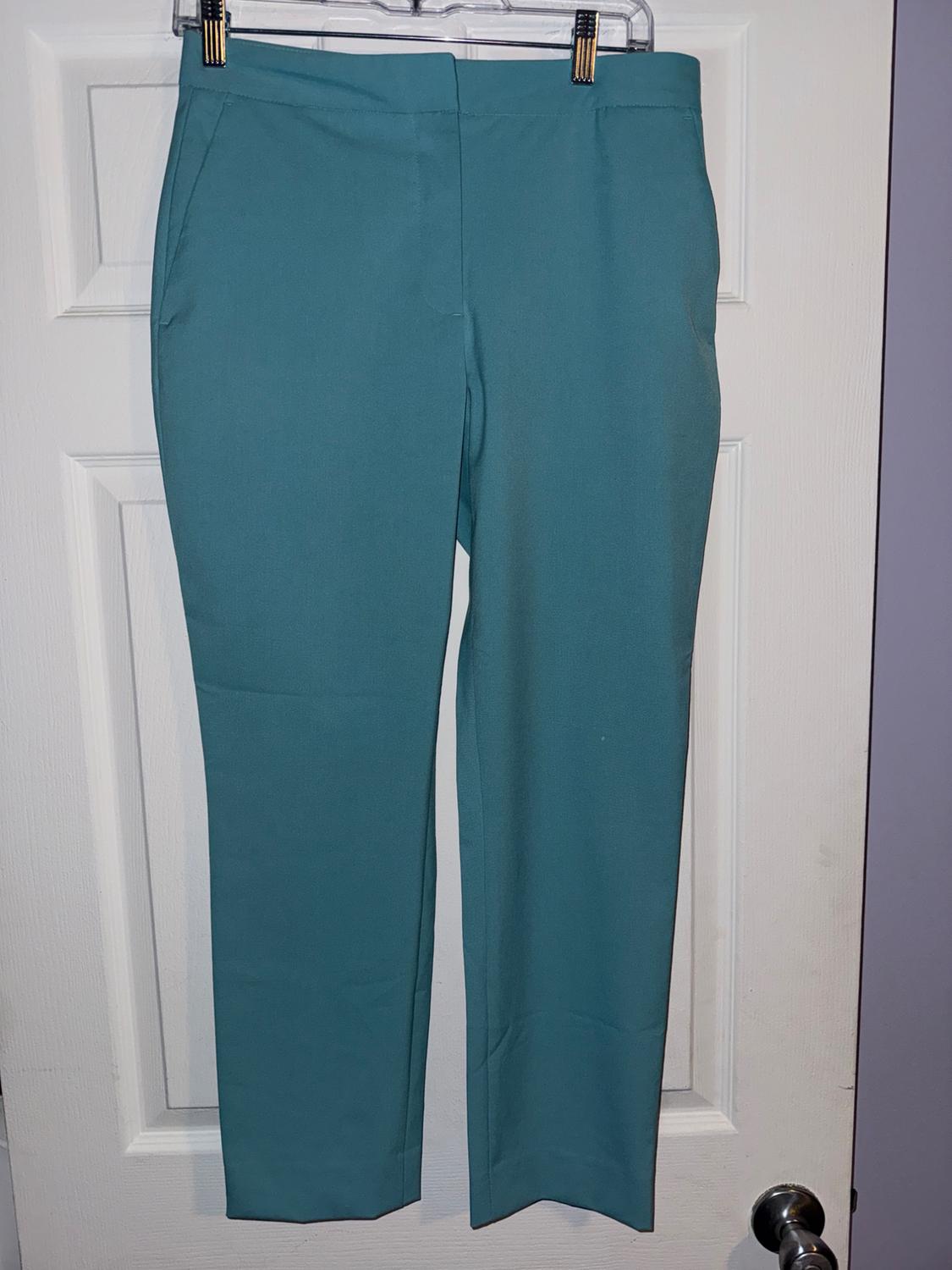 Turquoise blue trousers hanging on a hanger over a white door.