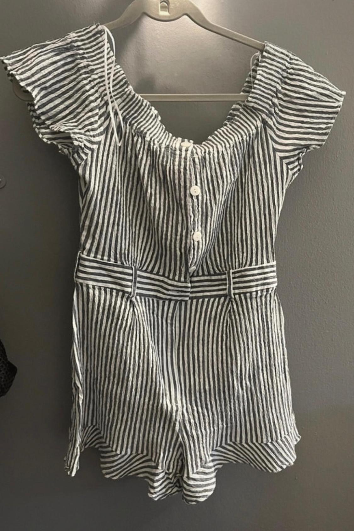 Front view of a black and white striped jumpsuit with front buttons and short sleeves.