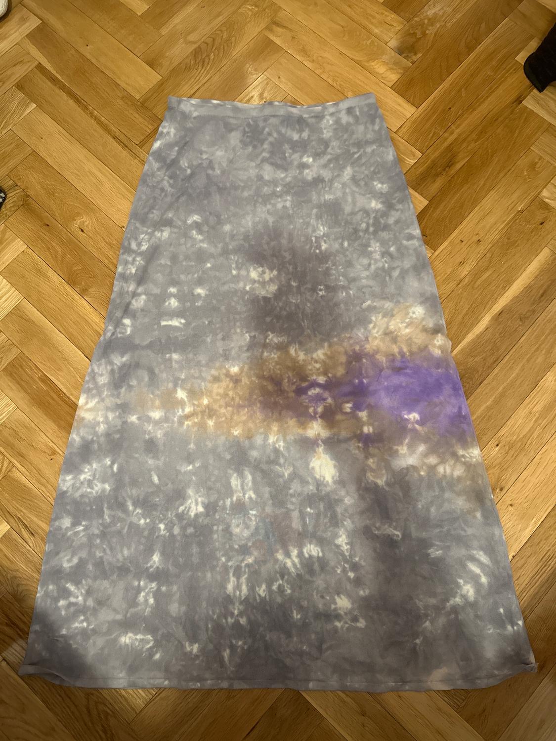 Long skirt with a tie-dye design in grey, brown, and purple tones, on a light wood floor.