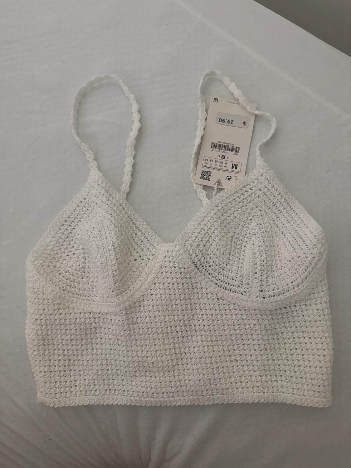 White crochet top with spaghetti straps on a white surface. Visible tag with price of £29.90.