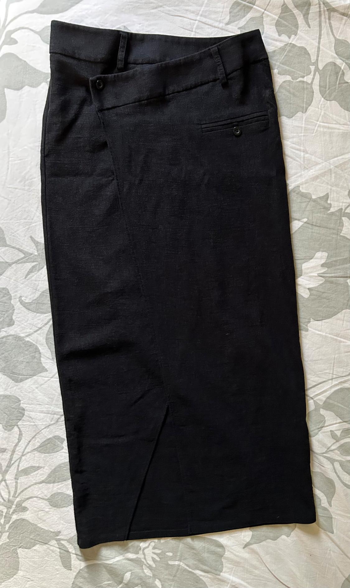 Black fabric skirt on a quilt with a grey leaf design. It has a back pocket with button and side zip fastening.