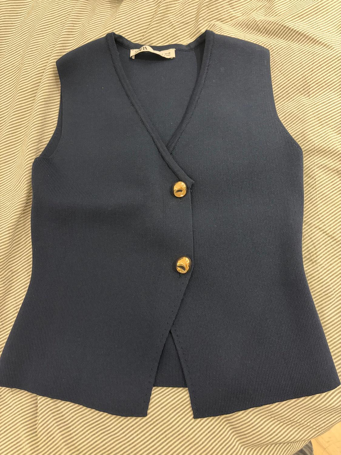 Navy sleeveless waistcoat with two gold buttons on beige and white striped fabric.