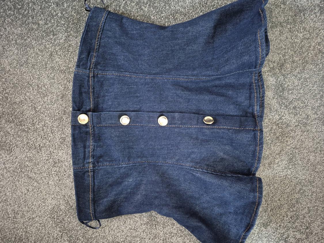 Blue denim skirt with gold buttons down the front, on a grey rug.