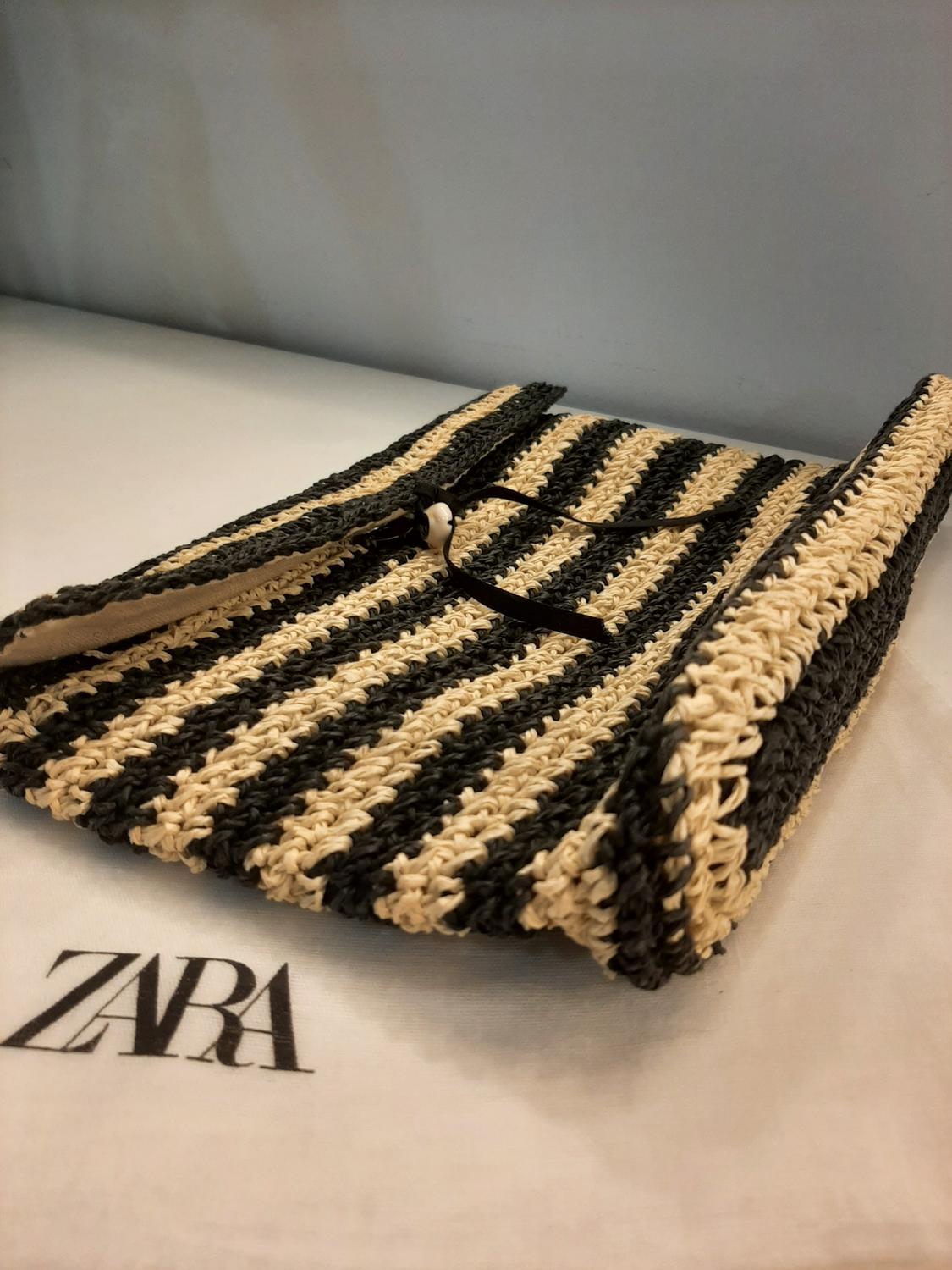 Detail of a black and beige striped bag with a button closure.