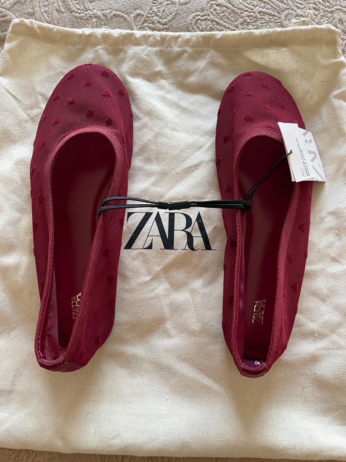 Maroon textured ballet flats on a fabric bag. Text: ZARA, AIRFIT TECHNICAL INSOLE FOAM.