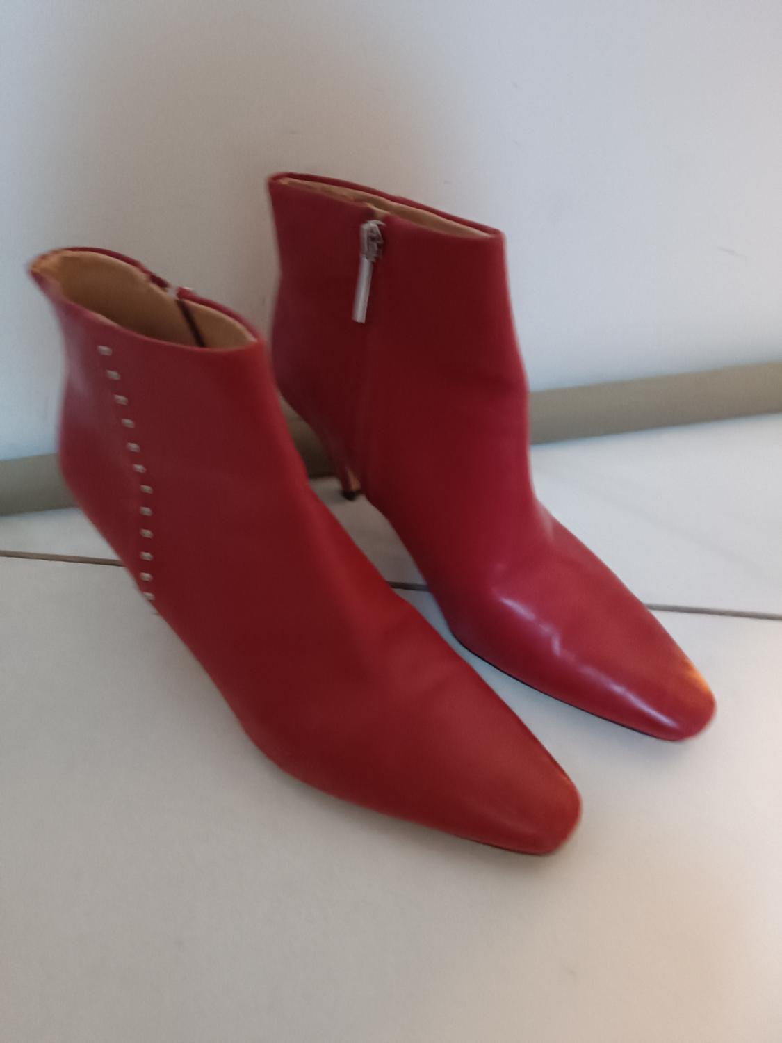 Red low-heeled ankle boots with a side zip and stud detailing, on a white background.