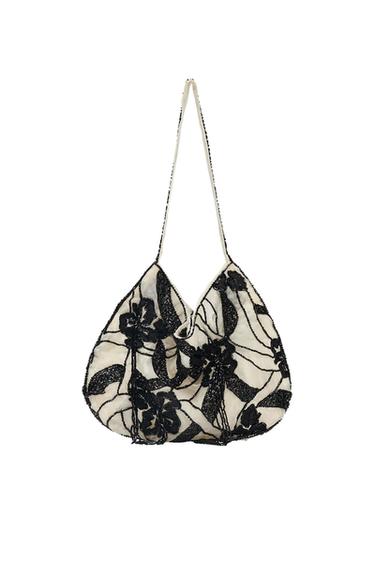 White handbag with black floral embroidery and a slim handle. Elegant and detailed design on a white background.