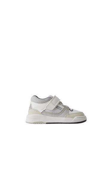 Side view of white and grey child's trainer with Velcro fastening.