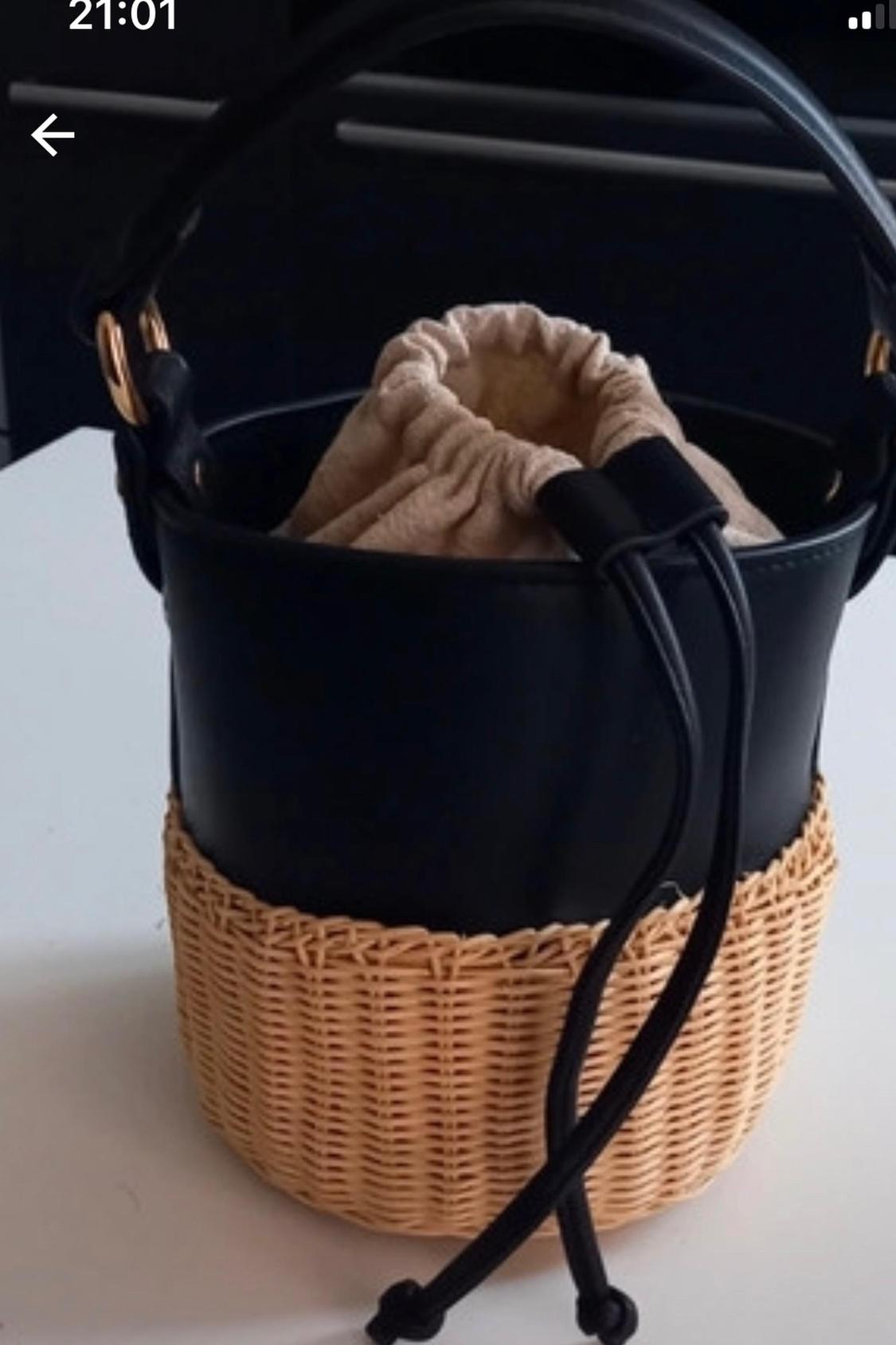 Detail of black bag with woven base and adjustable drawstring.