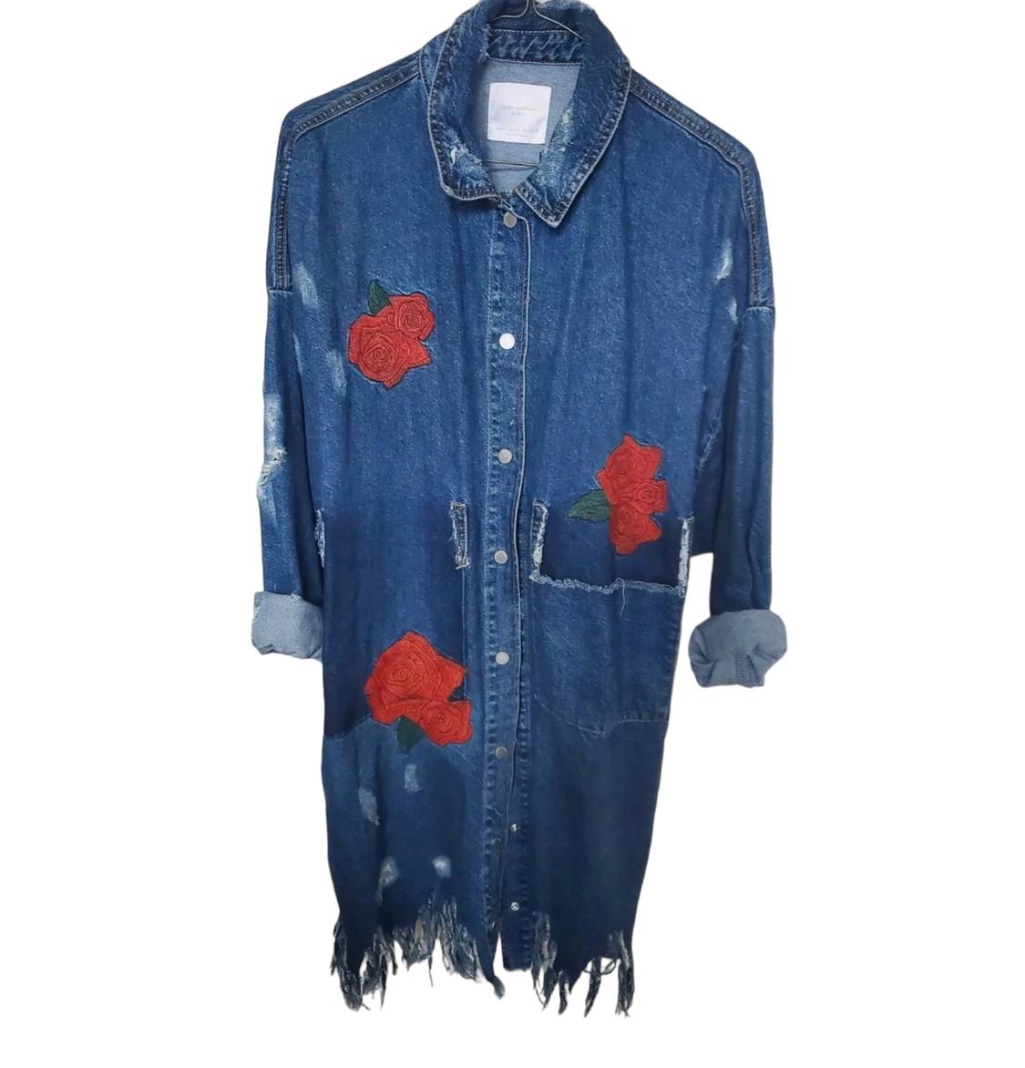 Front view of a denim jacket with embroidered roses and frayed hem.