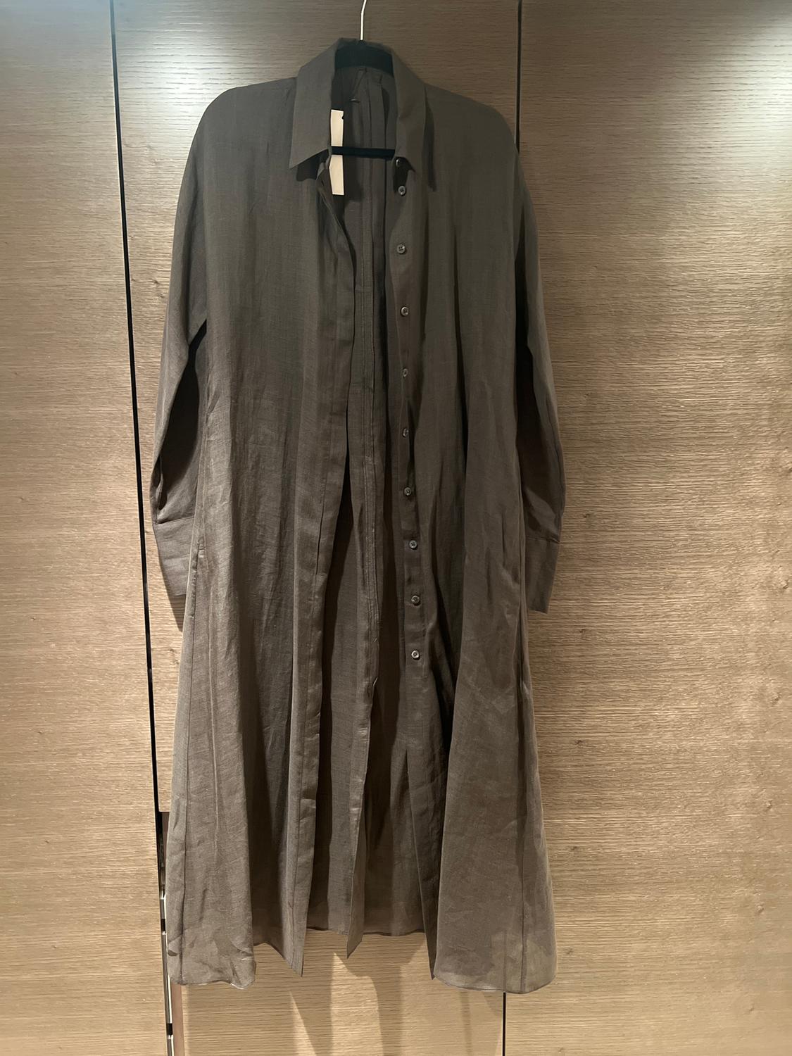 Dark grey long dress with front buttons, hanging on a hanger against a light wood background.