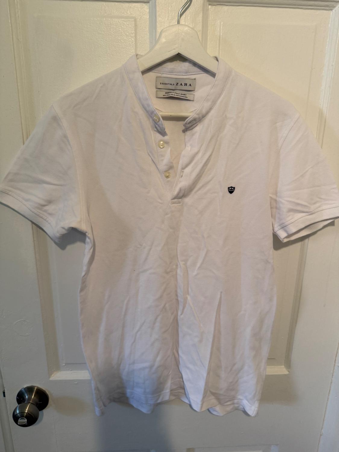 Front view of a white t-shirt with a mandarin collar and button fastening, small logo on the chest.