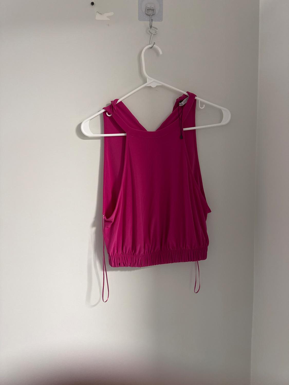 Front view of a pink sleeveless blouse with adjustable drawstrings and an elasticated hem.