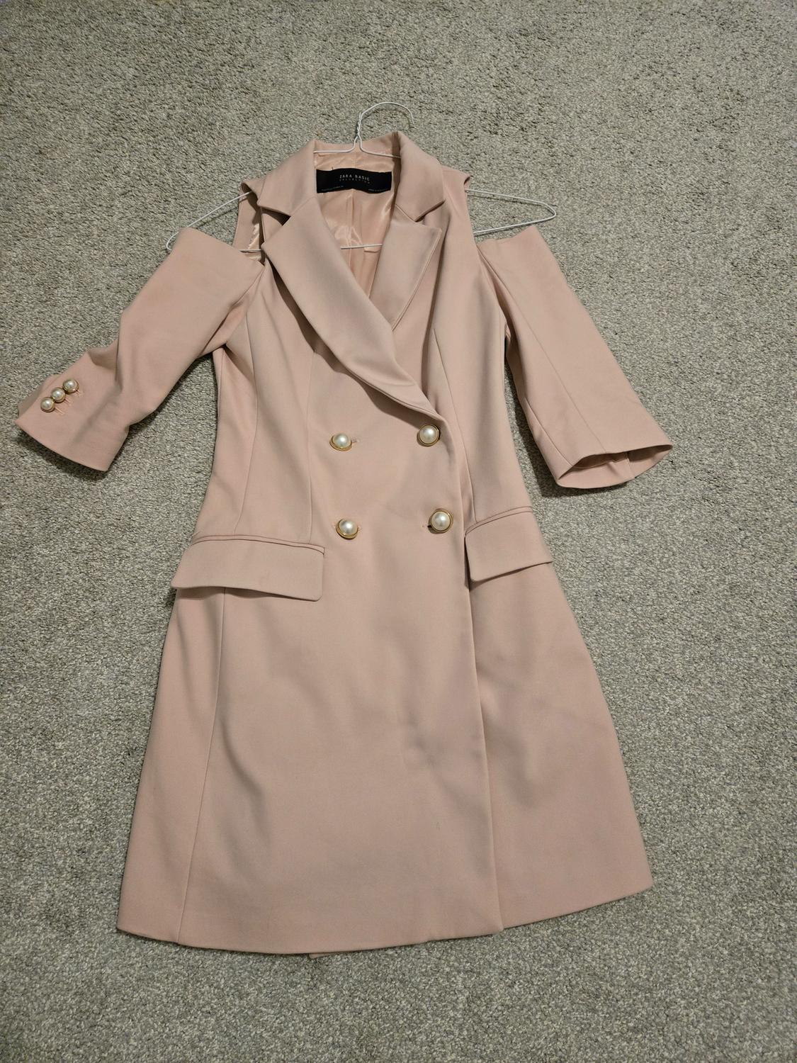 Front view of a pink coat with large lapels, gold buttons, and open sleeves.