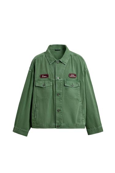 Front view of a green jacket with "Liam" and "World Racing Champs" patches, flap pockets on the chest and sides.