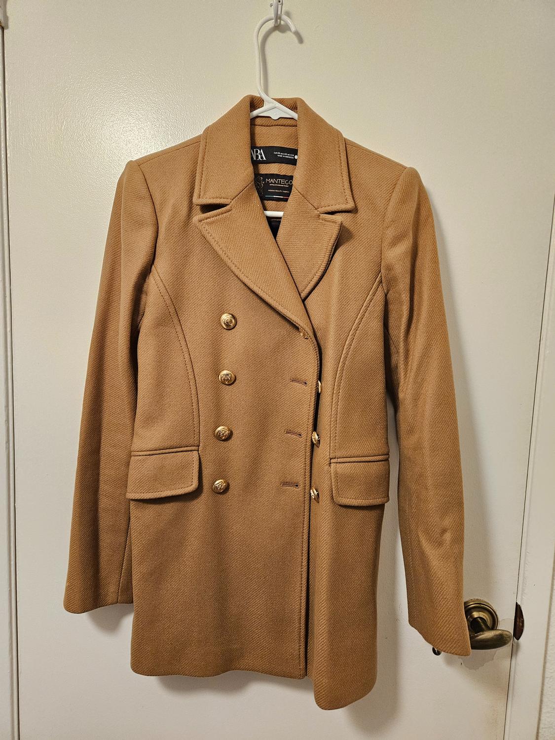 Front view of a camel coat with gold buttons and front flap pockets.