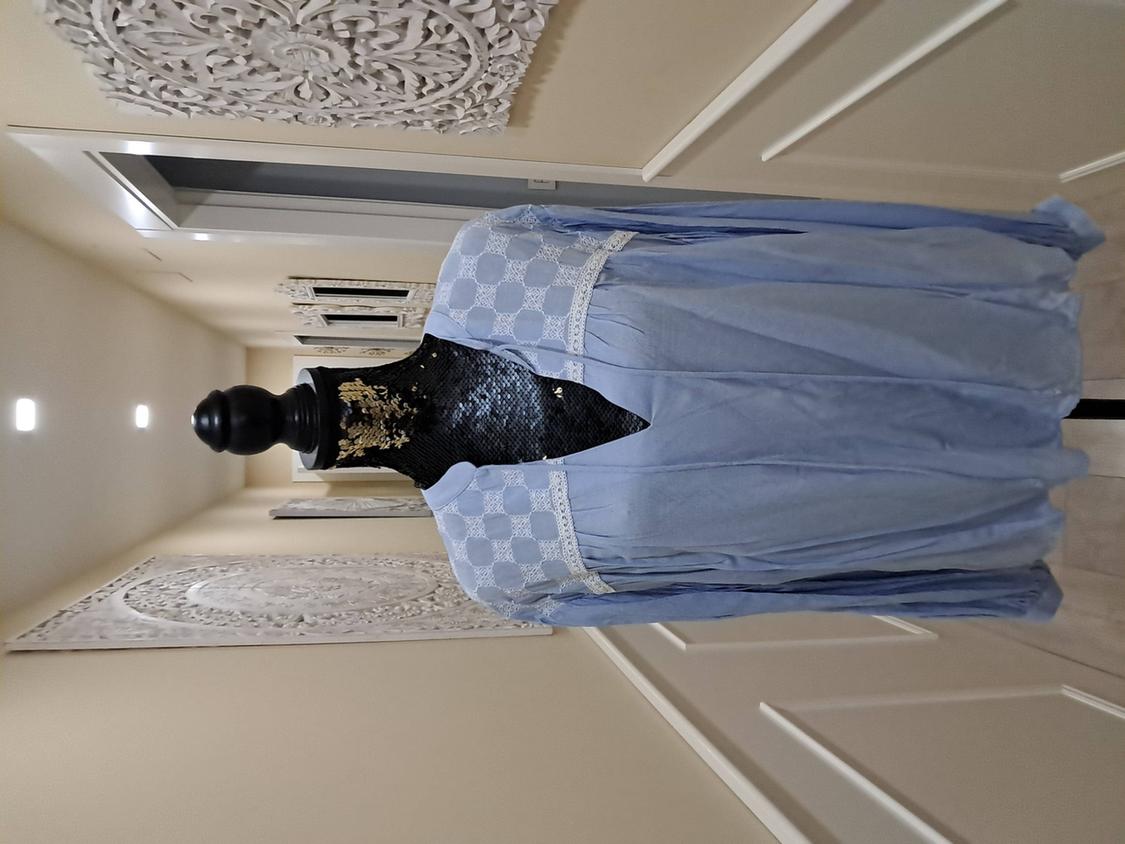 Mannequin in a light blue lace dress in an illuminated hallway, decorated with carved wooden panels on the walls.
