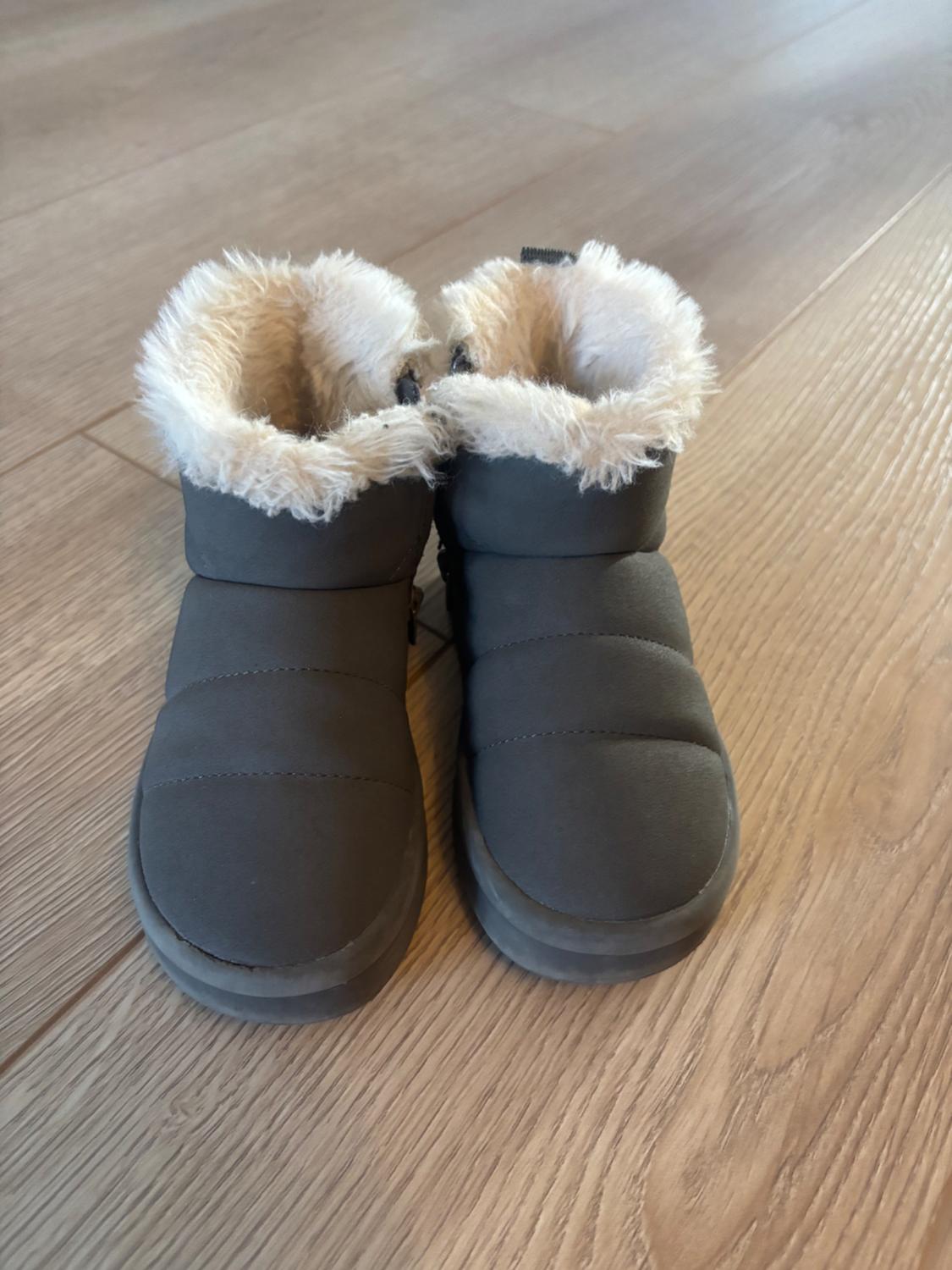 Grey boots with white faux fur lining, placed on a light wooden floor.