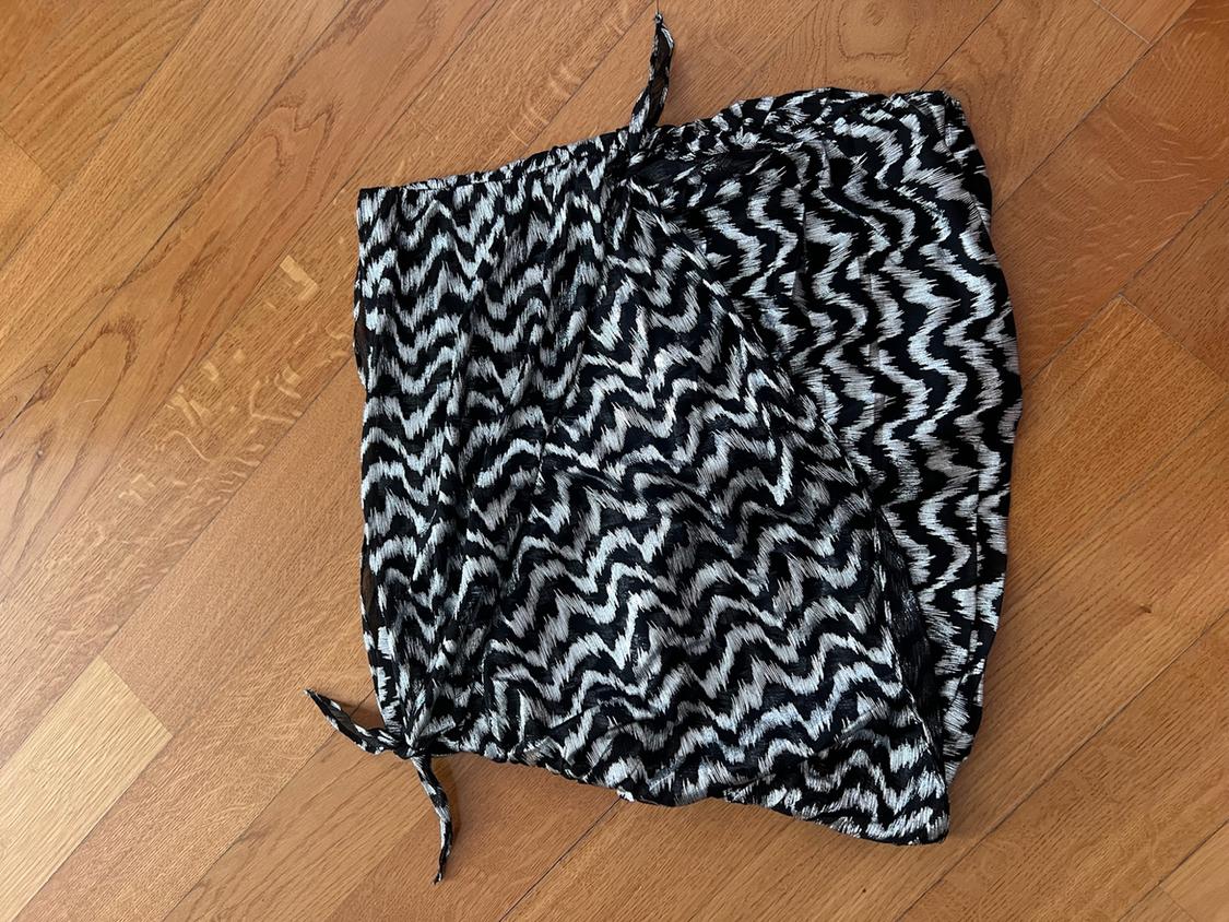 Garment with a black and white zigzag pattern and bow details, on a wooden floor.