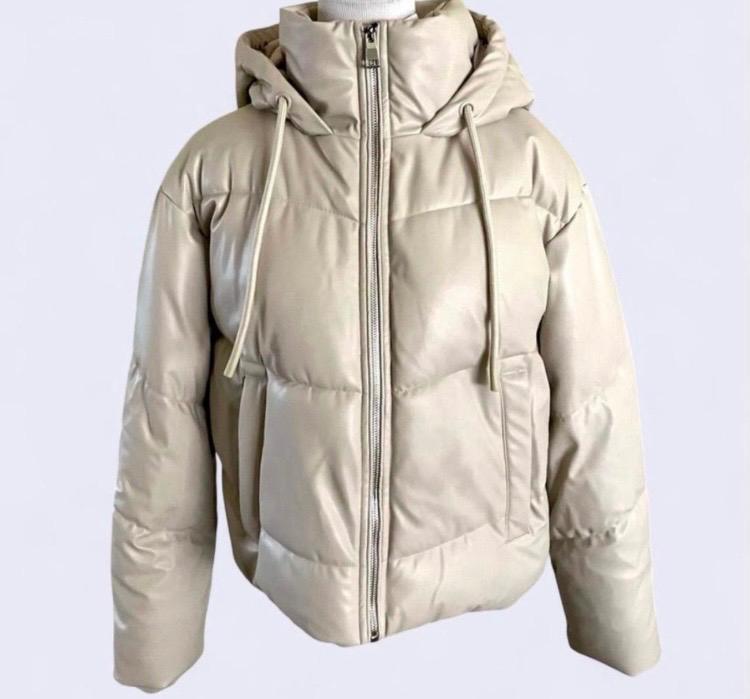 Beige padded jacket with hood and front zip fastening. Adjustable drawstrings on the hood. White background.