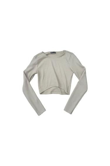 Light beige long-sleeved, crew-neck crop top in a ribbed knit, on a white background.