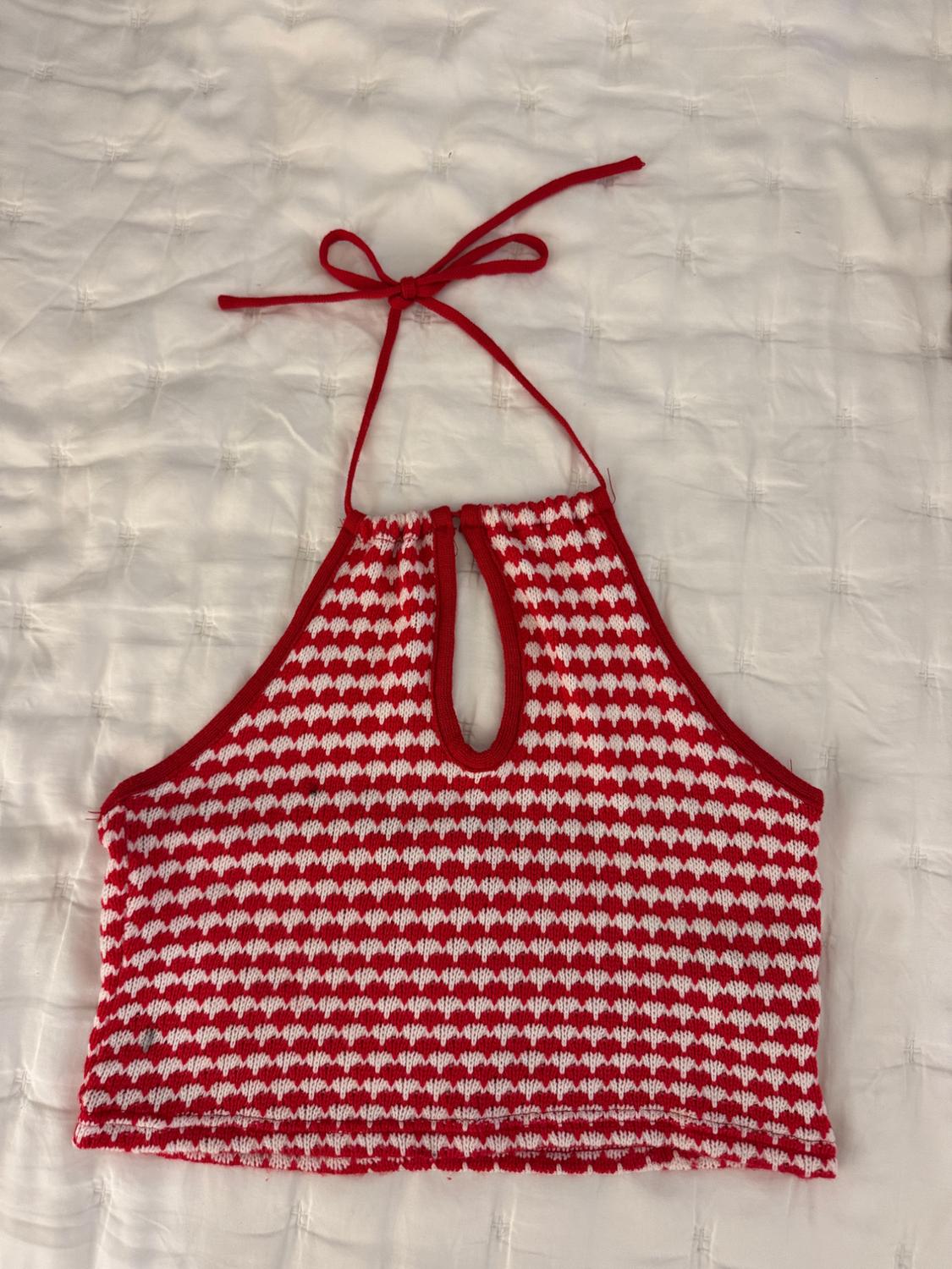 Red and white knitted top with triangle design, halter neck and front opening, on a white quilted bedspread.