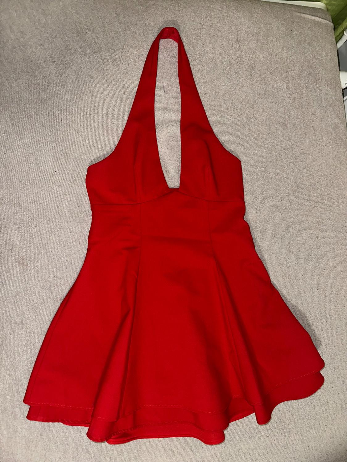 Backless red dress with a halter neckline, on a grey surface. Elegant and modern design.