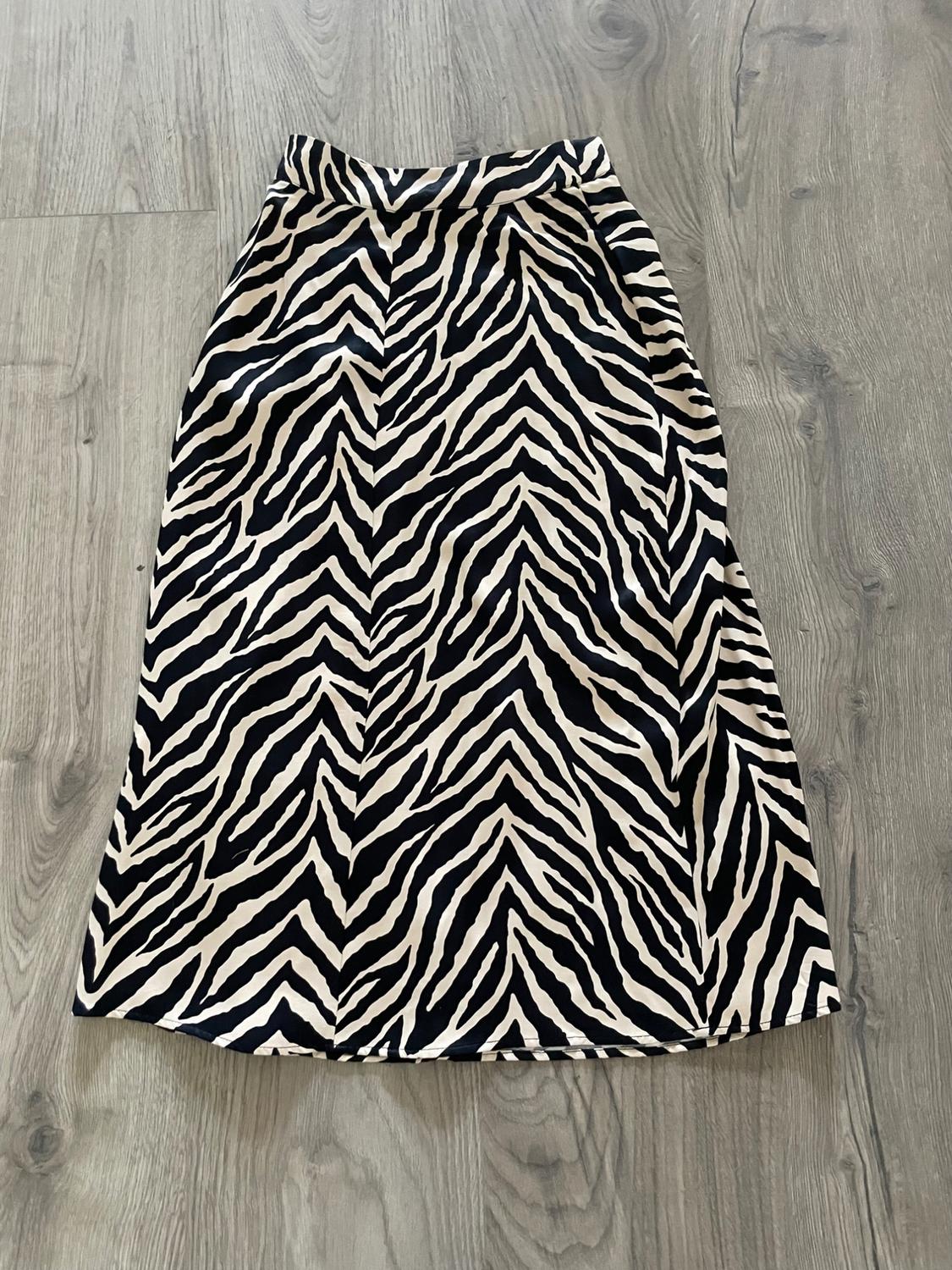 Black and white zebra print skirt on a gray wooden floor.