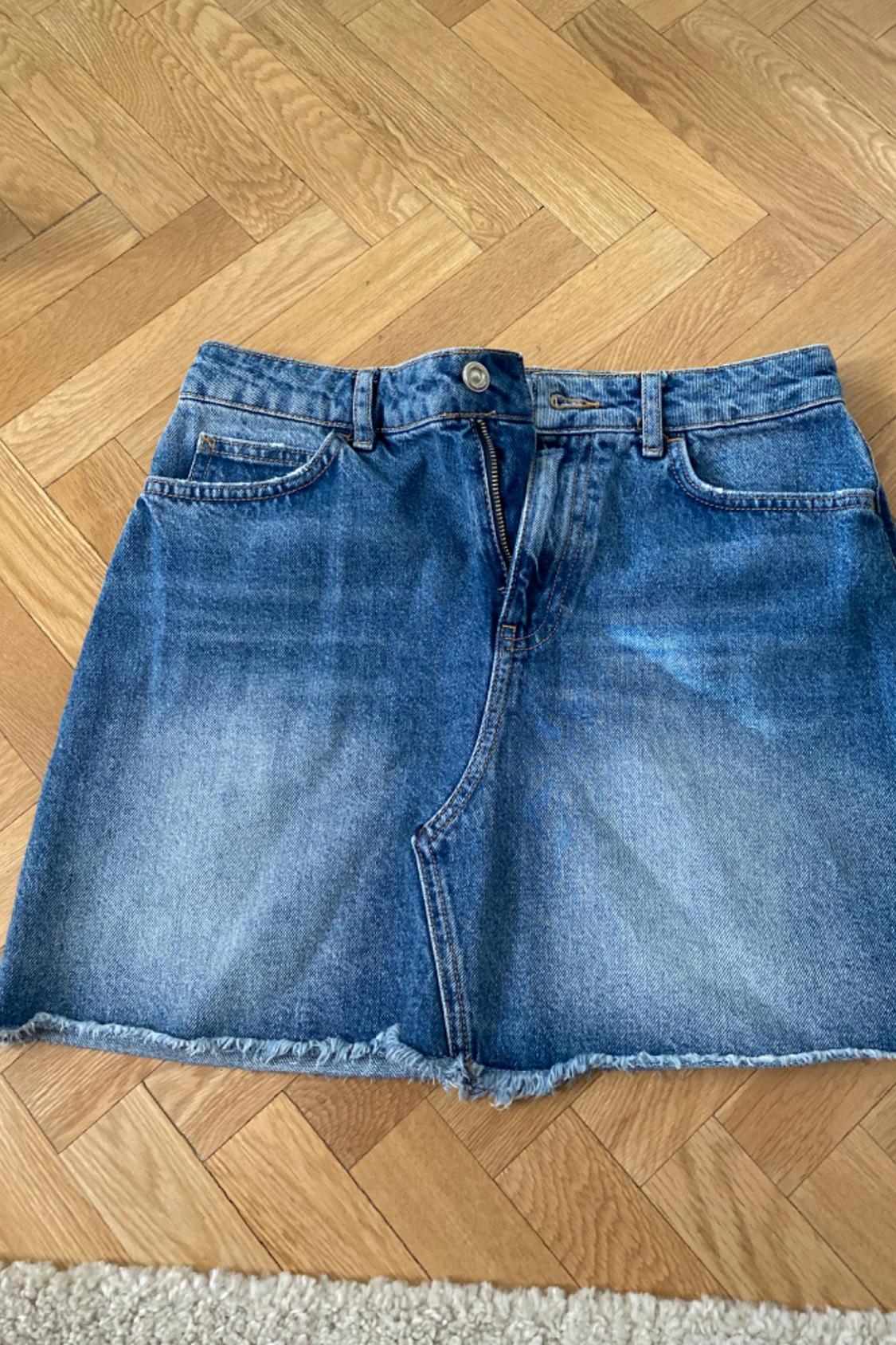 Front view of blue denim skirt with pockets and frayed hem.