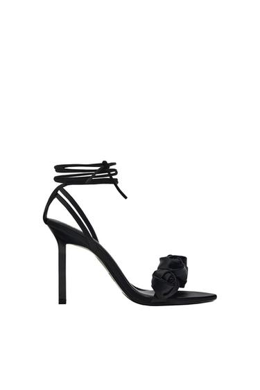 Side view of a black sandal with a high heel and ankle straps.