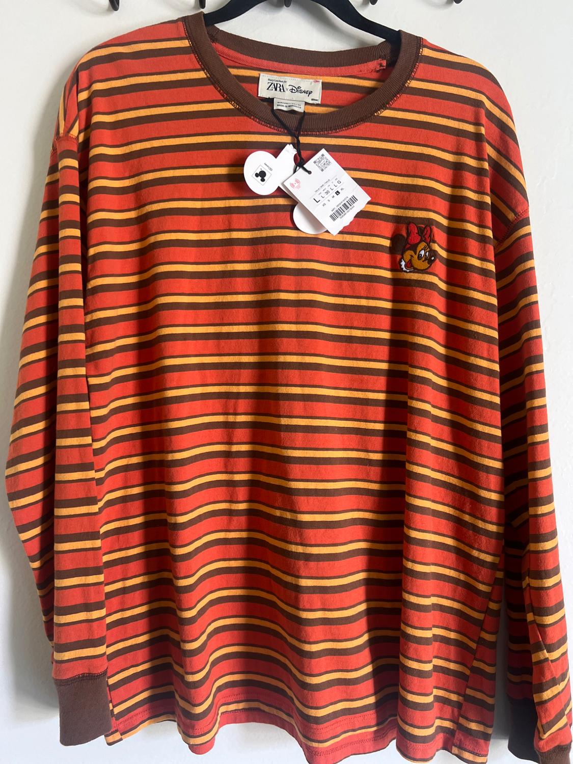 Orange and brown striped jumper with a crew neck and embroidered cartoon character. Visible hang tags.