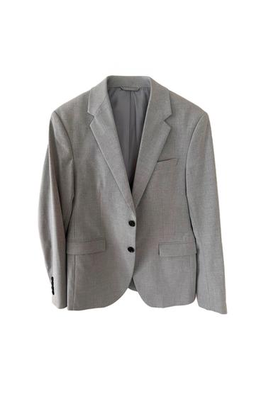Grey suit jacket with two black buttons and classic lapels. Front pockets with flaps. White background.