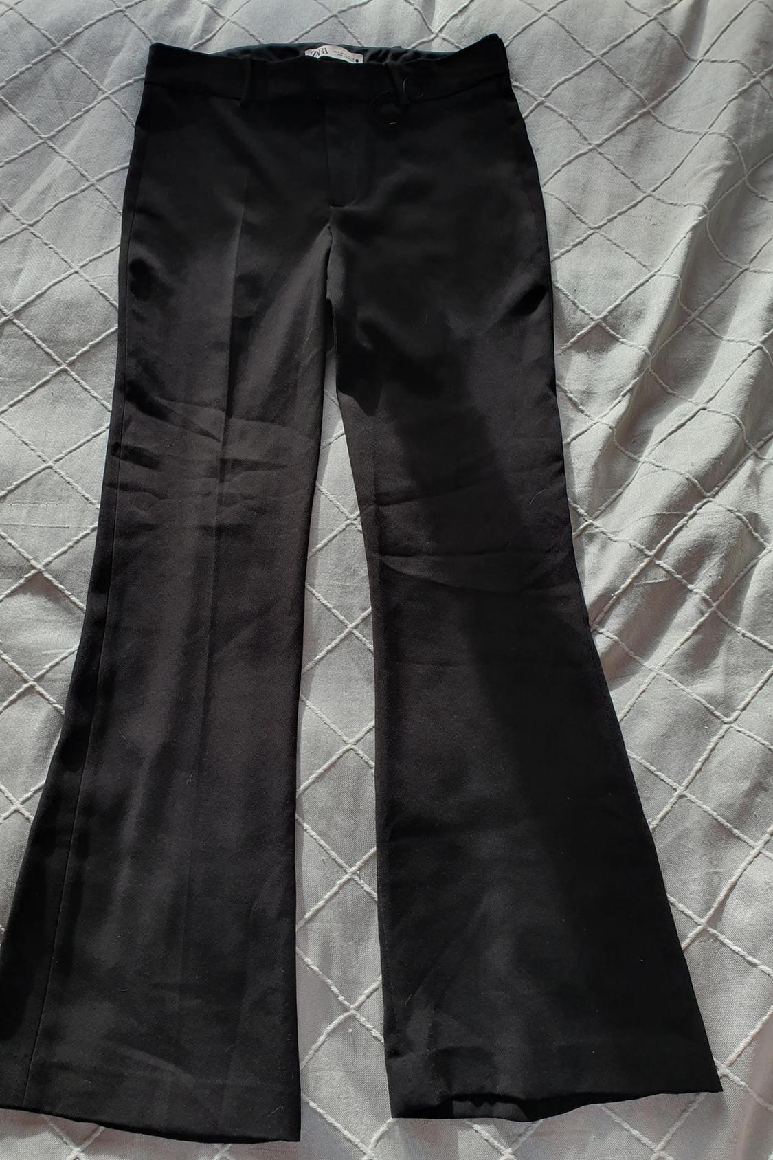 Front view of black flared-leg trousers with a waistband with belt loops.
