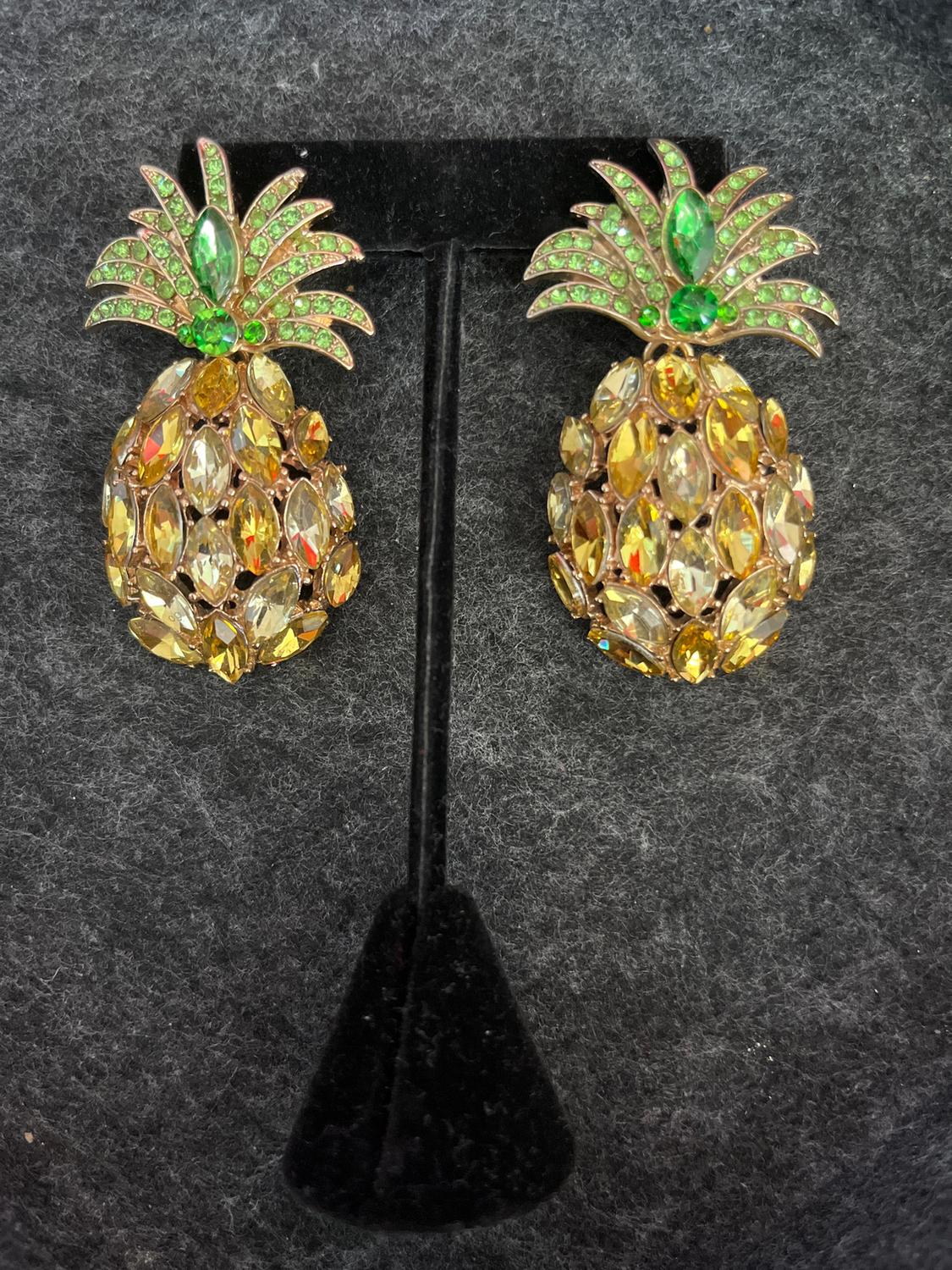 Pineapple-shaped earrings with yellow and green stones on a black background. Bright and eye-catching design.