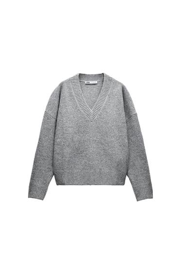 Grey knitted V-neck jumper with long sleeves. Visible label on the collar with the text "ZARA". White background.