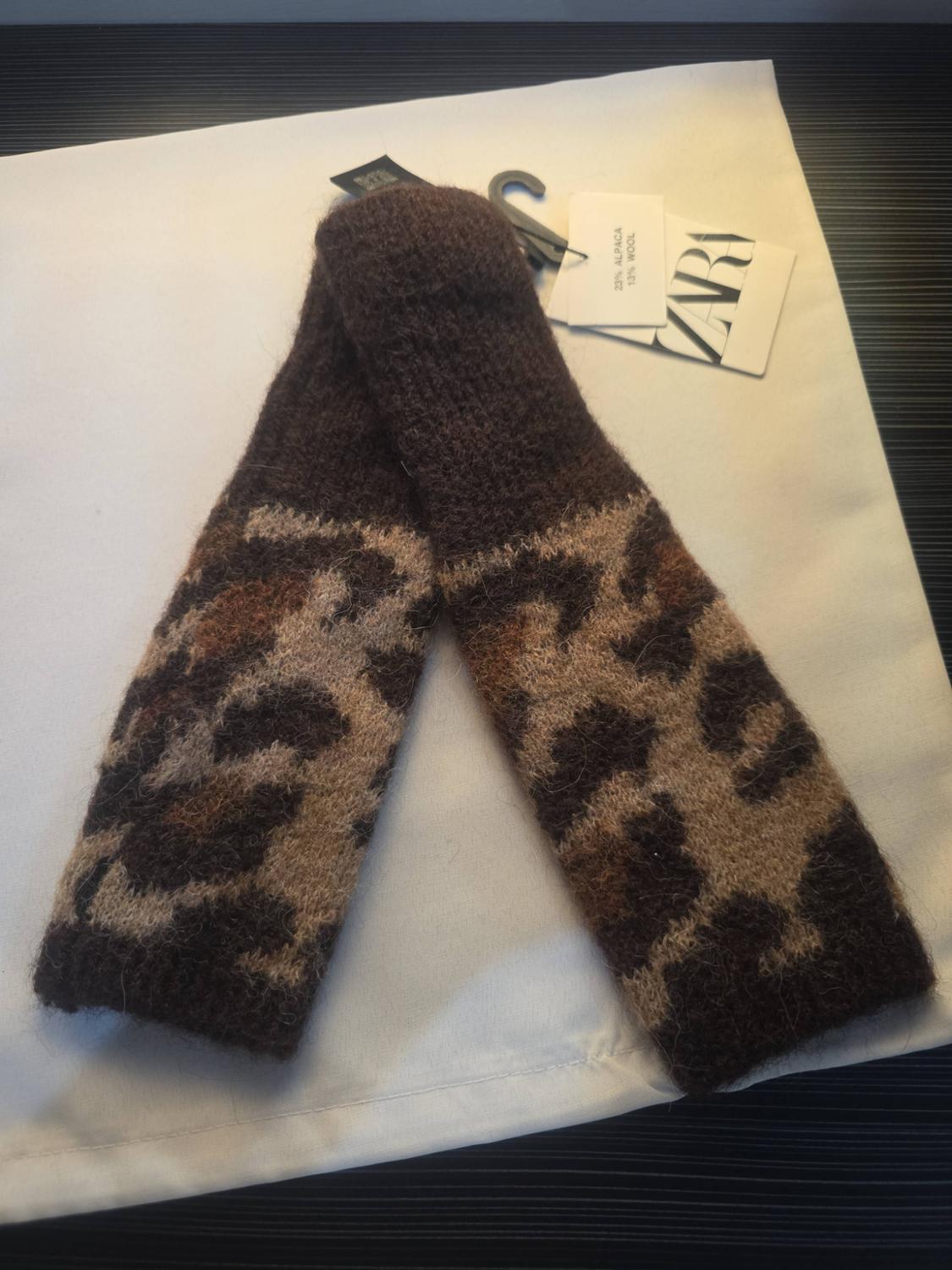 Brown knitted arm warmers with animal print. Labels with text: ZARA, 23% ALPACA 13% WOOL.