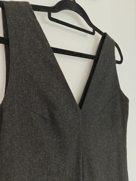 Dark grey V-neck dress hanging on a black hanger against a white background.