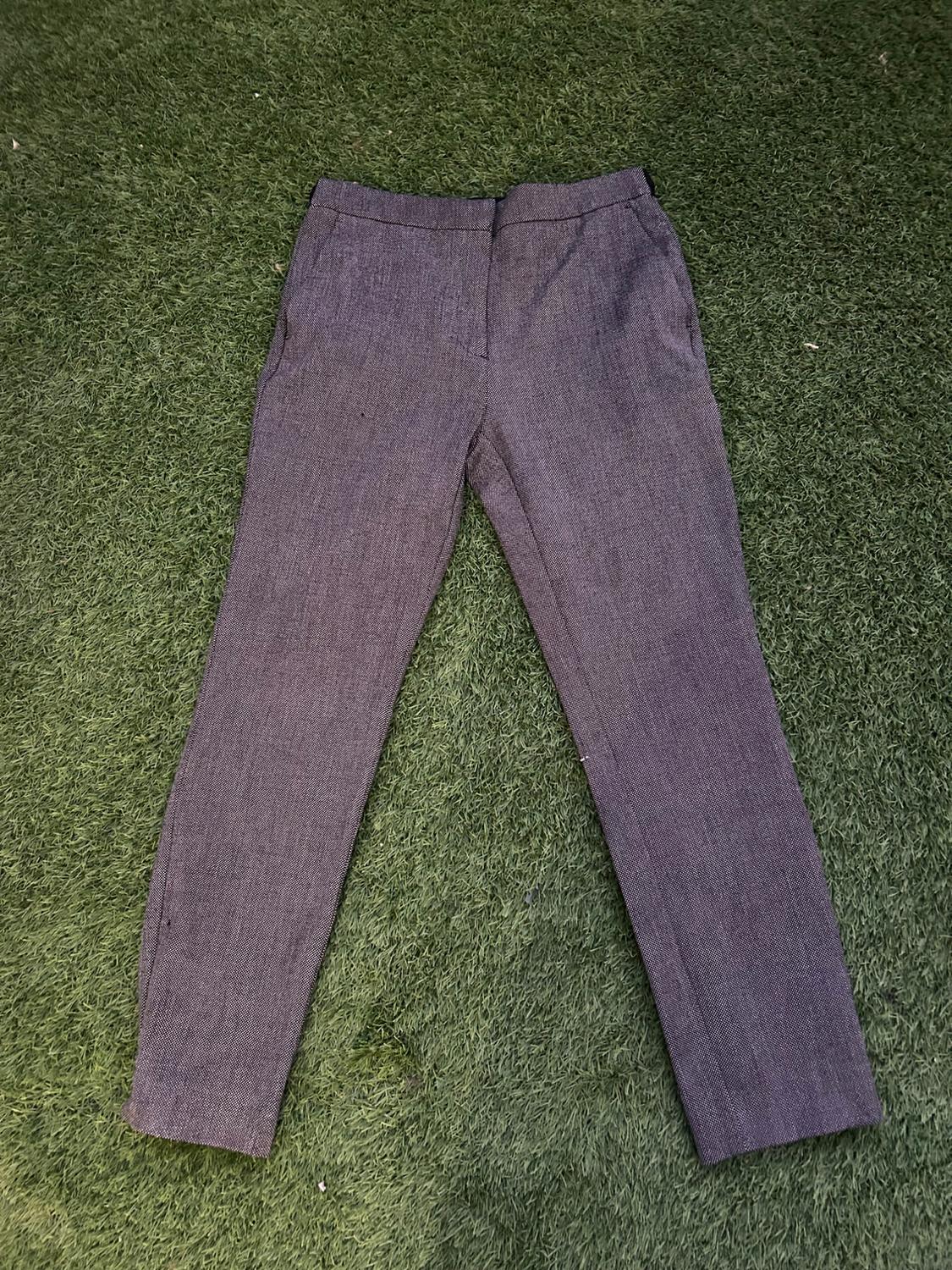 Grey fabric trousers on green grass, seen from above.