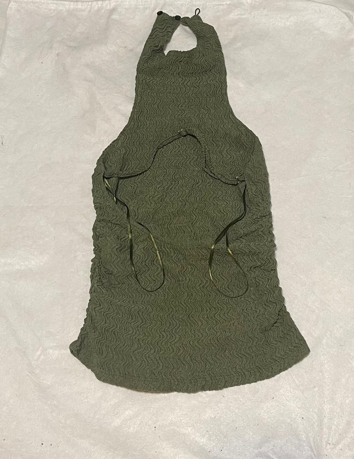 Olive green top with a wavy texture, halter neck, open back, and thin straps, on a wrinkled white fabric background.