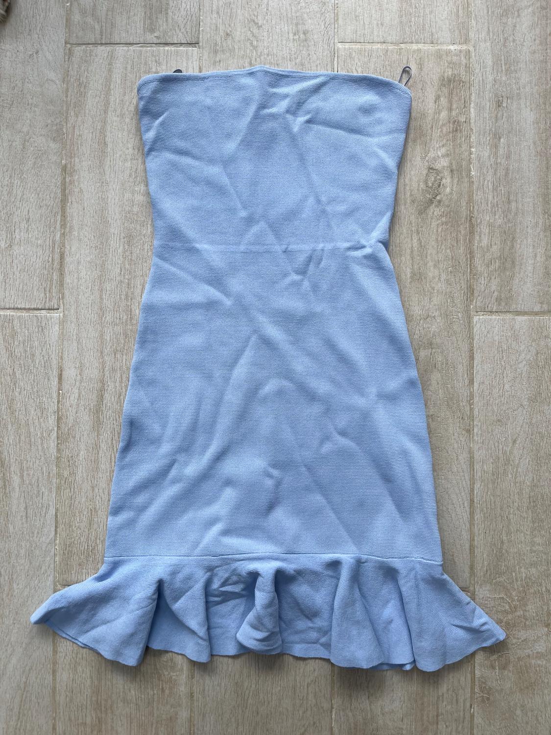 Light blue strapless dress with a soft texture and a frilled hem, placed on a beige wooden floor.