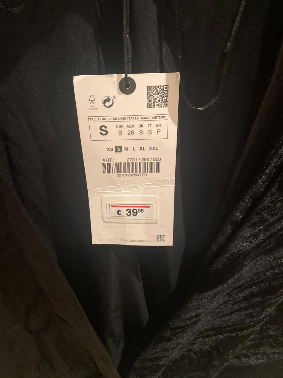 Clothing tag hanging from a black garment, showing sizes XS to XXL and price of €39.95. Item code: 2731/292/800.