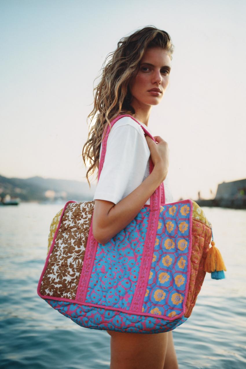 White short-sleeve t-shirt and quilted bag set featuring a multicolored floral patchwork print, pink handles, and a side pom-pom.