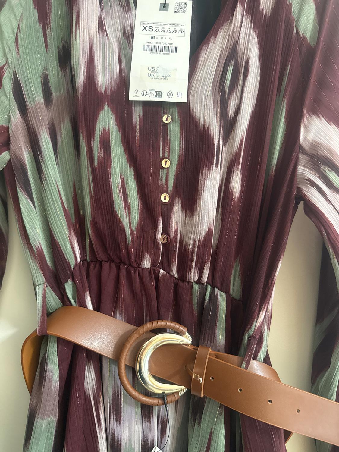 Dress with abstract print in burgundy and green tones, gold buttons and a brown belt with a gold buckle. Size XS tag visible.