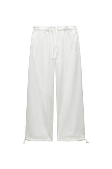 White, wide-leg trousers with an elasticated waist and adjustable drawstrings at the bottom, on a white background.